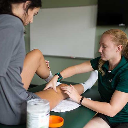 Athletic training student assisting an athlete.